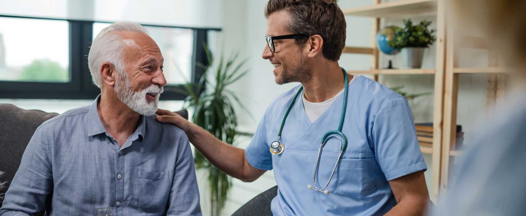 young male doctor speaking with old male patient both smiling